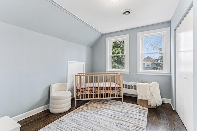 bedroom featuring visible vents, baseboards, vaulted ceiling, and wood finished floors