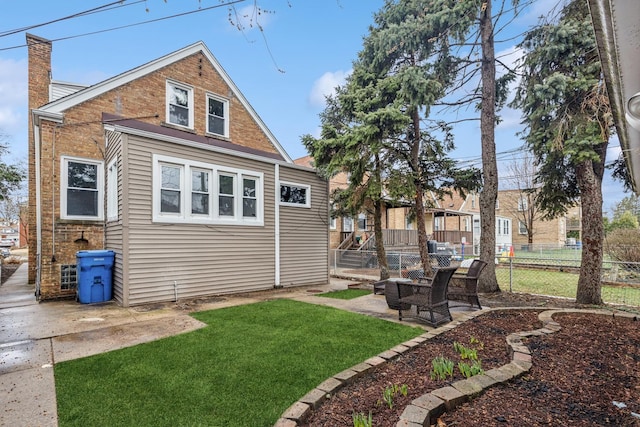 back of property featuring fence, a patio, a chimney, and a lawn