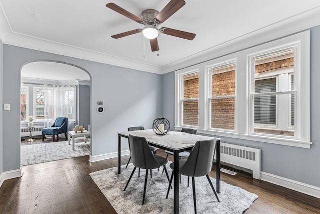 dining area with radiator heating unit, arched walkways, and baseboards