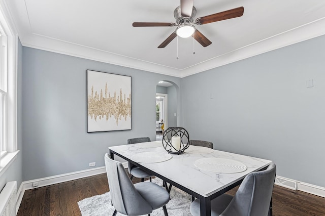 dining room with baseboards, a ceiling fan, crown molding, arched walkways, and wood finished floors