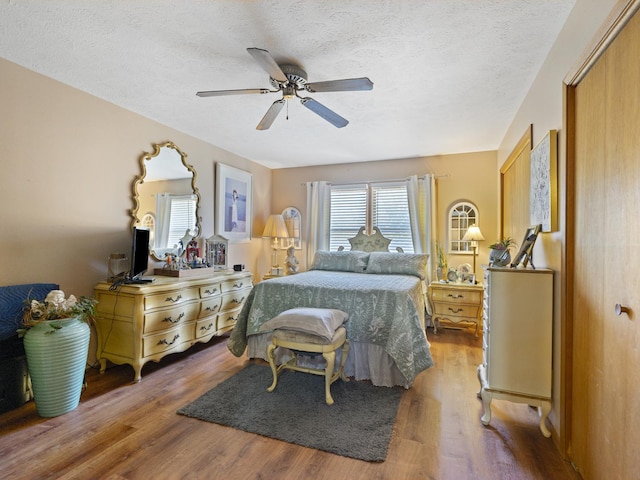 bedroom with wood finished floors, ceiling fan, and a textured ceiling