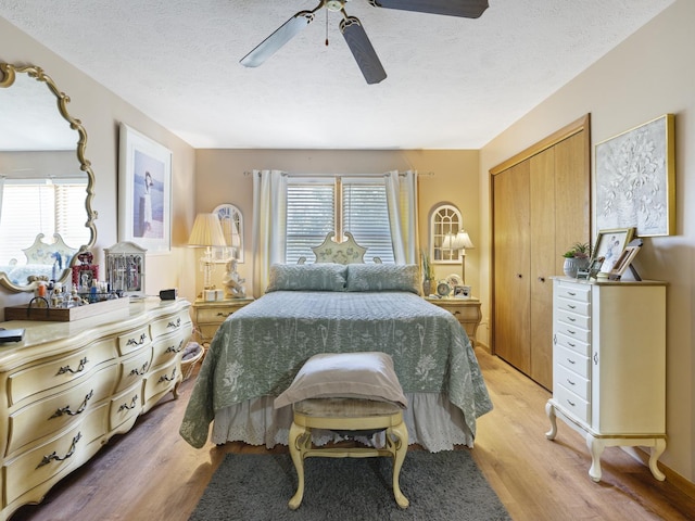 bedroom with a ceiling fan, light wood-style floors, a textured ceiling, and a closet