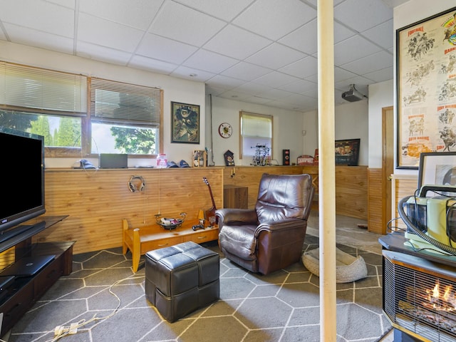 living area featuring a paneled ceiling and wainscoting