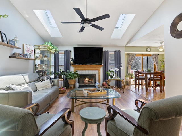 living room with a skylight, ceiling fan, and wood finished floors