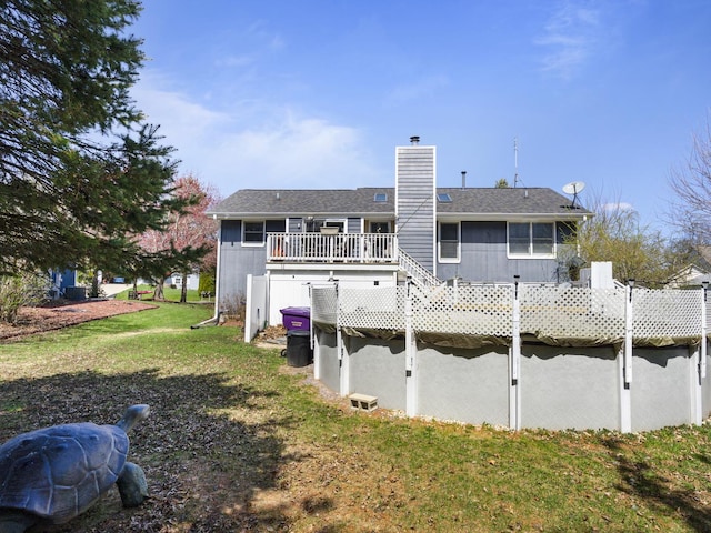 rear view of property featuring a lawn, a wooden deck, and a chimney
