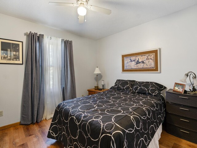 bedroom with wood finished floors, ceiling fan, and baseboards