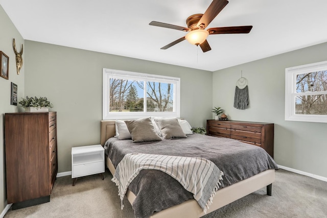 carpeted bedroom featuring multiple windows, baseboards, and ceiling fan