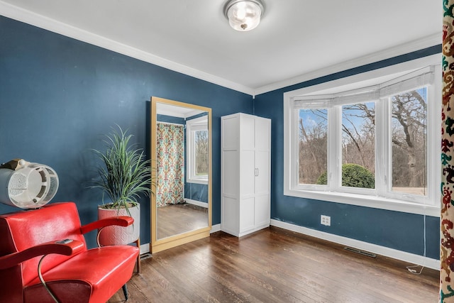 living area with wood-type flooring, visible vents, baseboards, and crown molding