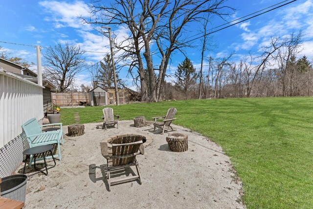 view of yard featuring a patio, an outdoor structure, a shed, an outdoor fire pit, and fence