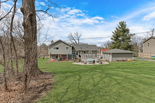 rear view of property featuring an outbuilding, a wooden deck, a lawn, and a chimney
