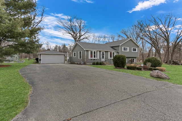 tri-level home featuring an outbuilding, a detached garage, and a front lawn