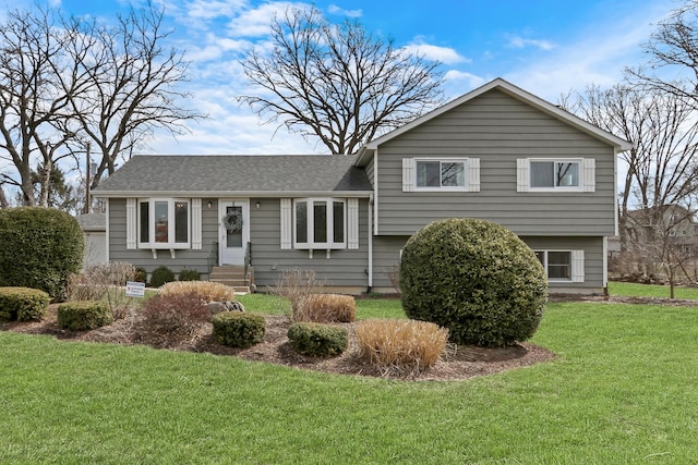 rear view of house with a yard and roof with shingles