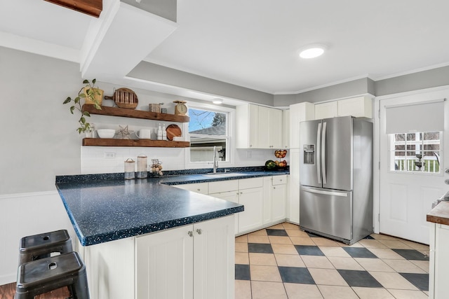 kitchen featuring stainless steel fridge, a peninsula, open shelves, white cabinets, and a sink