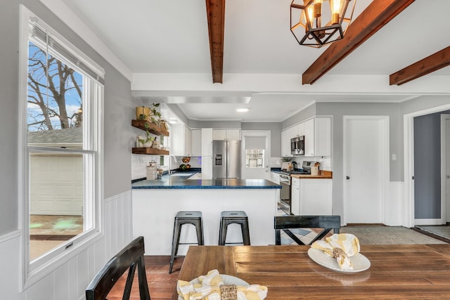 dining space with beamed ceiling, a wainscoted wall, an inviting chandelier, and wood finished floors