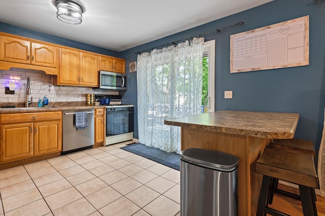 1407 Centennial Dr, Champaign, IL 61821 - kitchen with stainless steel appliances, tasteful backsplash, light tile patterned flooring, dark countertops, and a breakfast bar