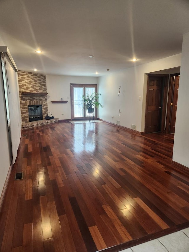 11723 S S Ave J, Chicago, IL 60617 - unfurnished living room featuring wood-type flooring, visible vents, and a brick fireplace
