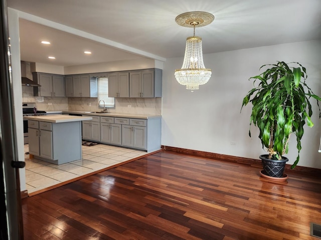 11723 S S Ave J, Chicago, IL 60617 - kitchen featuring wall chimney exhaust hood, gas stove, light countertops, light wood finished floors, and gray cabinetry