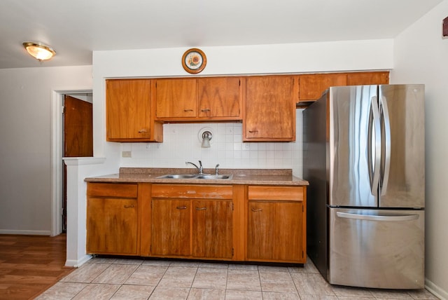 640 W 95th St, Chicago, IL 60628 - kitchen featuring freestanding refrigerator, brown cabinetry, tasteful backsplash, a sink, and baseboards