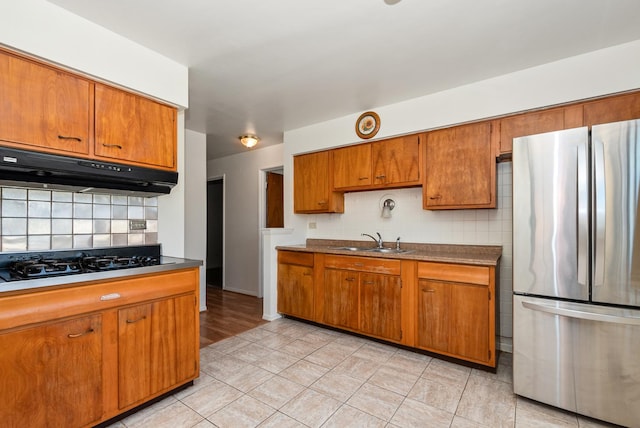 640 W 95th St, Chicago, IL 60628 - kitchen featuring tasteful backsplash, freestanding refrigerator, black gas stovetop, under cabinet range hood, and brown cabinetry