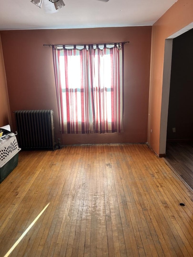 spare room featuring wood-type flooring and radiator heating unit