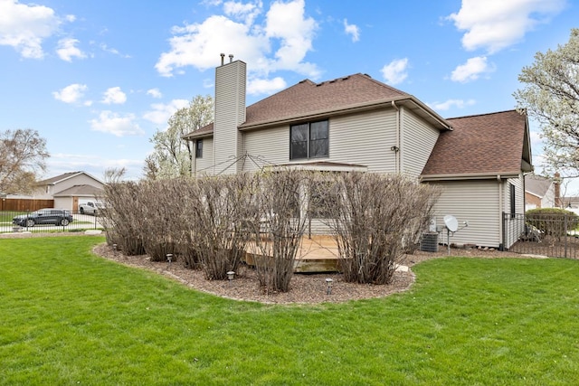 back of property with a lawn, fence, a chimney, and roof with shingles