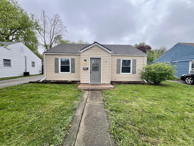 bungalow with a shingled roof and a front lawn