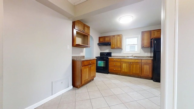 kitchen with a sink, brown cabinetry, black appliances, and under cabinet range hood