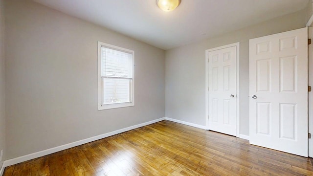 unfurnished bedroom with baseboards, wood finished floors, and a closet