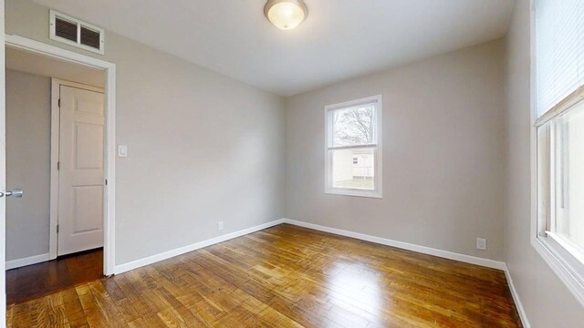 empty room with baseboards, visible vents, and wood finished floors