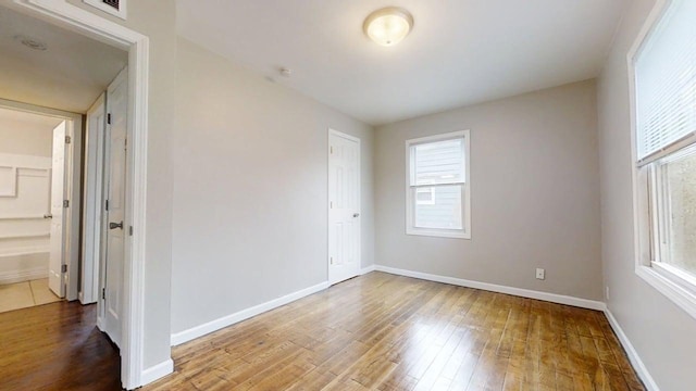 spare room featuring baseboards, wood finished floors, and visible vents