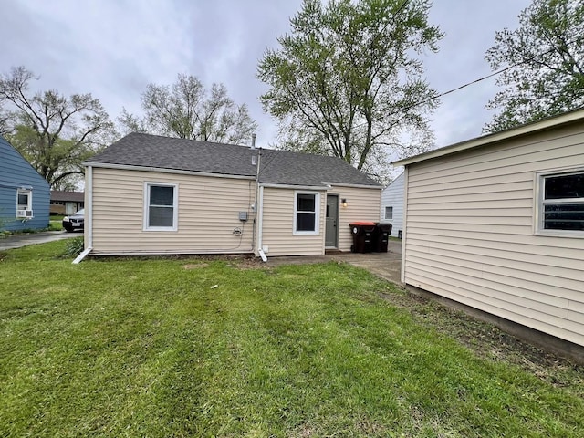 back of property featuring a yard and roof with shingles