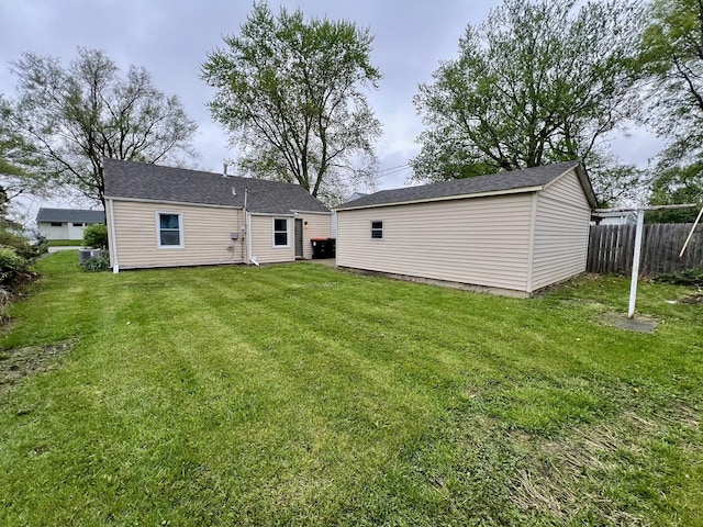 back of house with fence, an outbuilding, and a yard