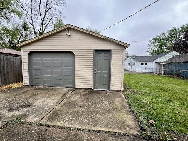detached garage featuring fence and driveway