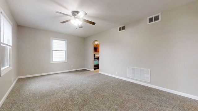 empty room featuring visible vents, arched walkways, and a ceiling fan