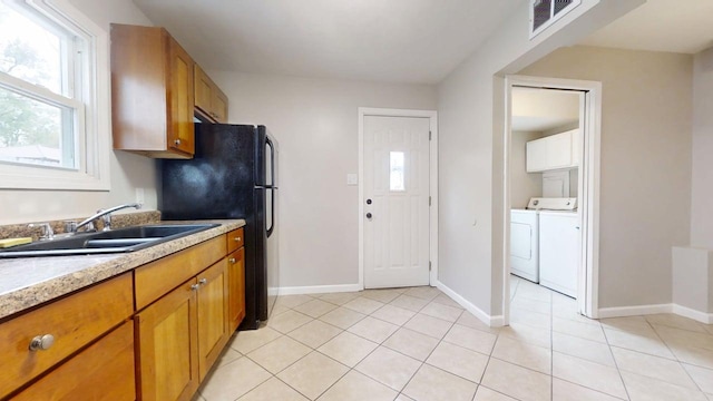 kitchen featuring brown cabinetry, a sink, washer and dryer, and visible vents