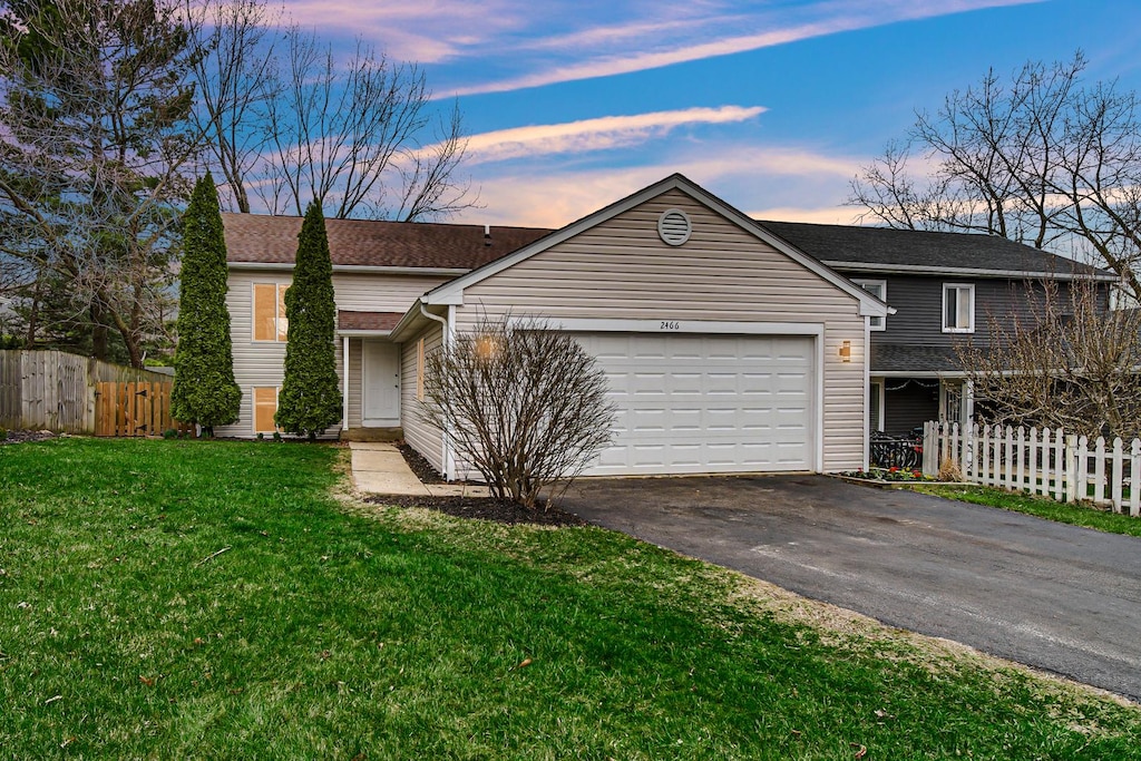 2466 Sunlight Ct, Aurora, IL 60502 - view of front of house with an attached garage, fence, driveway, and a front lawn
