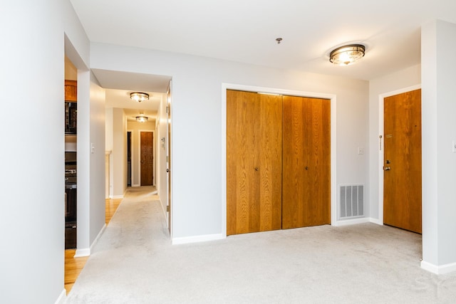 unfurnished bedroom with light colored carpet, baseboards, visible vents, and a closet