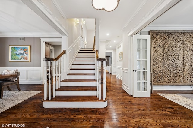 stairs featuring wood finished floors, a decorative wall, a wainscoted wall, and visible vents