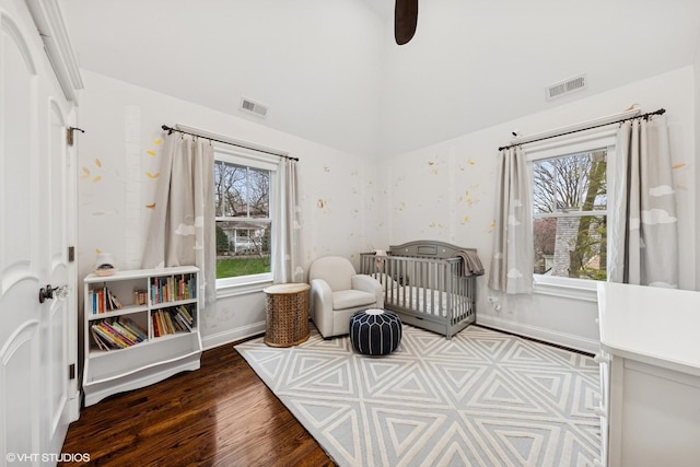 bedroom with lofted ceiling, visible vents, baseboards, and wood finished floors