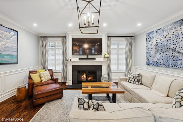 living area with a decorative wall, wood finished floors, a notable chandelier, and crown molding