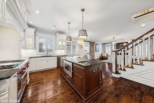 kitchen featuring stainless steel appliances, a sink, ornamental molding, and dark wood-style flooring
