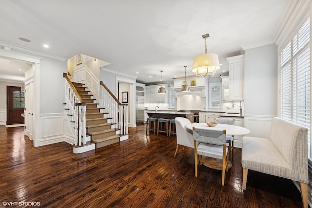 dining area featuring ornamental molding, a wainscoted wall, stairs, and dark wood-style floors