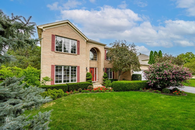 traditional-style house with brick siding, a front yard, and a garage