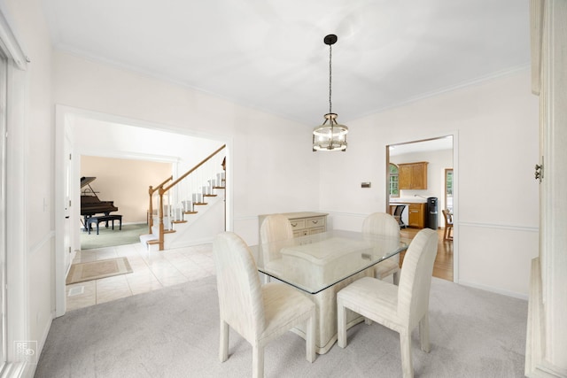 dining space with baseboards, light carpet, ornamental molding, and stairway
