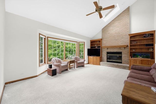 carpeted living room featuring a brick fireplace, baseboards, high vaulted ceiling, a ceiling fan, and a skylight