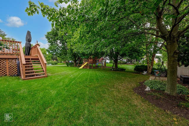 view of yard featuring a deck, stairs, and a playground