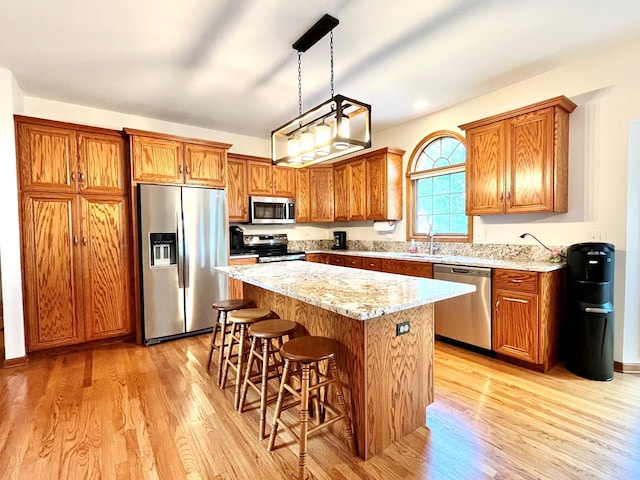 kitchen featuring light wood finished floors, appliances with stainless steel finishes, brown cabinets, and a kitchen island