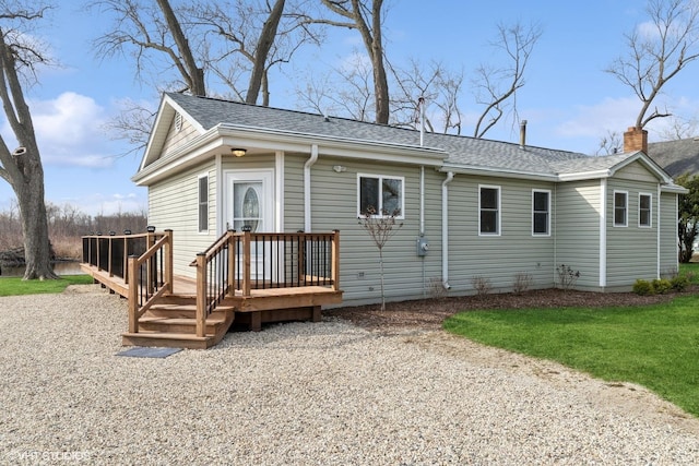 back of property featuring a wooden deck, a shingled roof, and a chimney