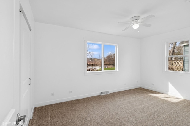 spare room featuring a wealth of natural light, a ceiling fan, carpet flooring, and baseboards