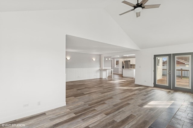 unfurnished living room featuring high vaulted ceiling, wood finished floors, wainscoting, ceiling fan, and french doors
